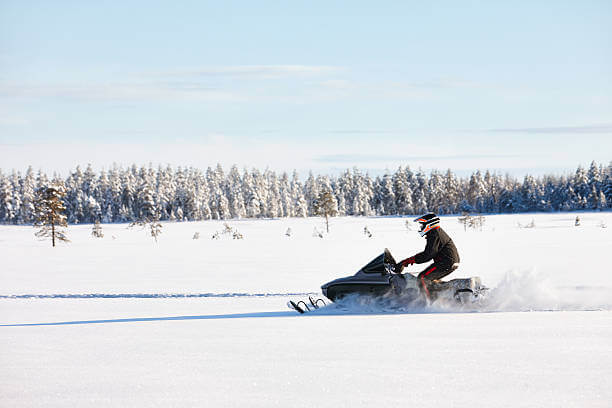 Man driving sports snowmobile in Finnish Lapland in a sunny day